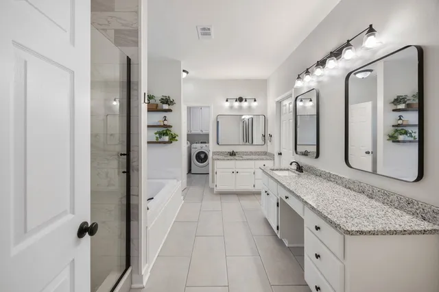 a large bathroom with a granite countertop double vanity sink a mirror and a bathtub