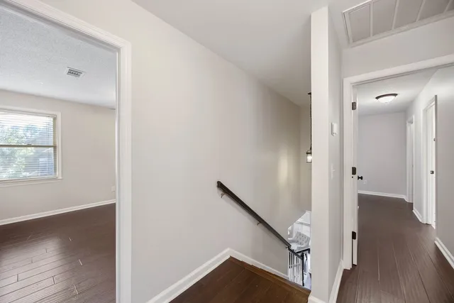 a view of a hallway with wooden floor and stairs