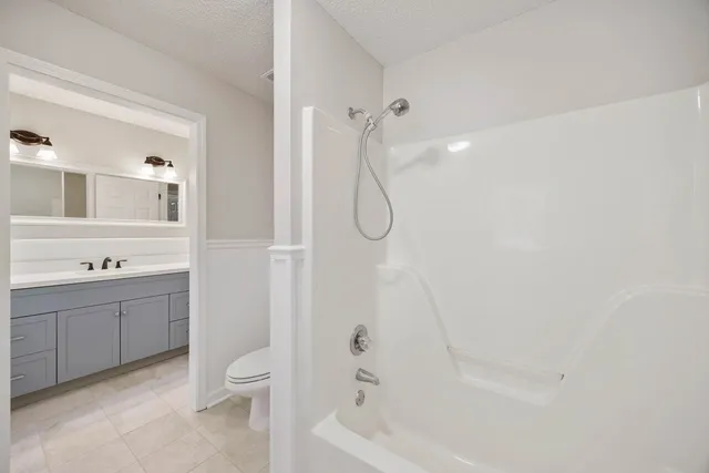 a bathroom with a bathtub shower sink vanity and toilet