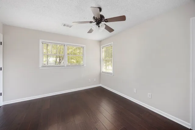 a view of empty room with wooden floor and fan
