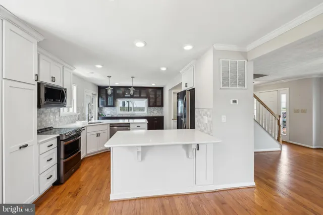 a large kitchen with stainless steel appliances granite countertop a refrigerator a stove top oven a sink and dishwasher with wooden floor