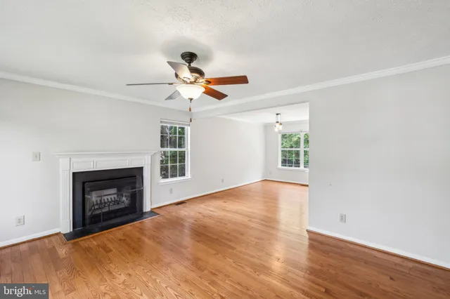 a view of an empty room with wooden floor fireplace and a window
