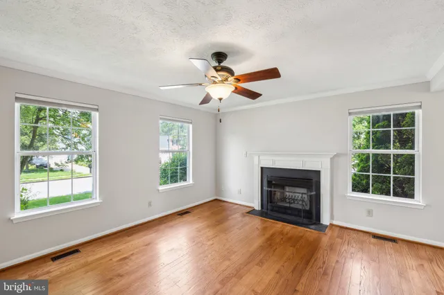 a view of an empty room with wooden floor fireplace and a window