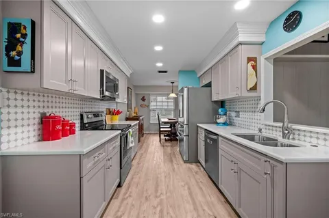 a kitchen with kitchen island granite countertop lots of counter top space a sink a stove and a wooden floors