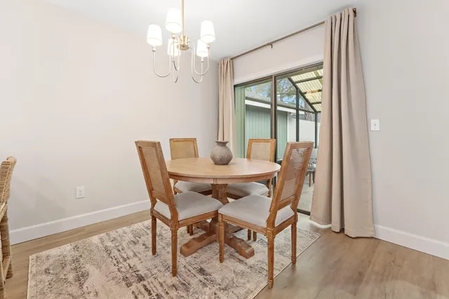 a dining room with wooden floor a chandelier a wooden table and chairs