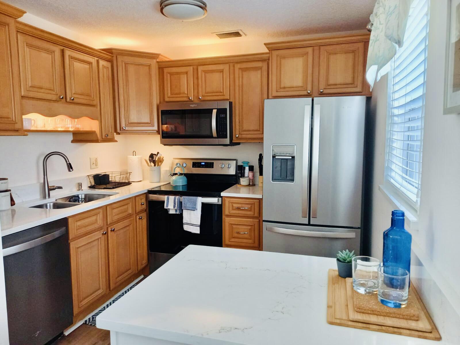 80 Crooked Tree Lane, Unit 106 Vero Beach, FL 32962 - Photo 21 of 47 a kitchen with stainless steel appliances granite countertop a refrigerator sink stove microwave and cabinets