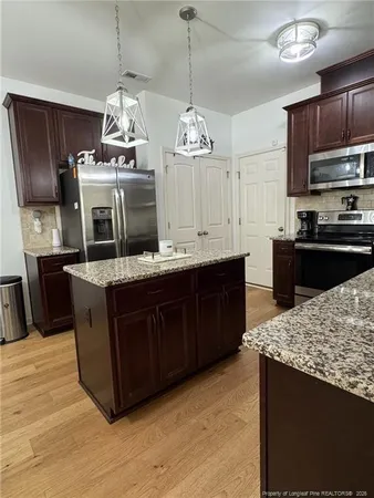 a kitchen with a stove a sink and wooden floor