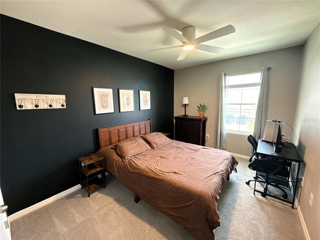 8446 Hardy Bay Loop Wesley Chapel, FL 33545 - Photo 14 of 38 a bedroom with a bed and a chandelier