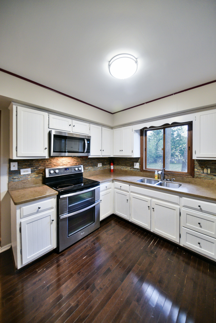 755 Cumnock Road Olympia Fields, IL 60461 - Photo 8 of 34 a large kitchen with stainless steel appliances granite countertop a stove a sink dishwasher a microwave oven with cabinets and wooden floor