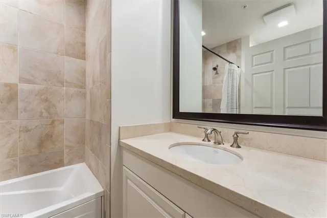 a bathroom with a granite countertop sink and a bathtub