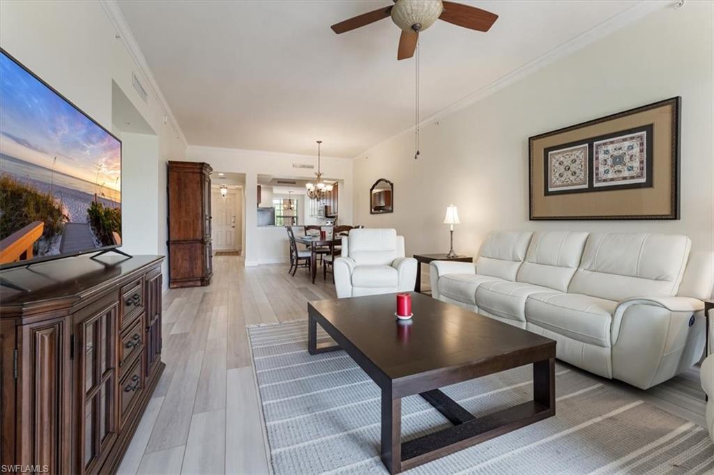 5080 Annunciation Circle, Unit 204 Ave Maria, FL 34142 - Photo 6 of 24 a living room with furniture a rug and a chandelier