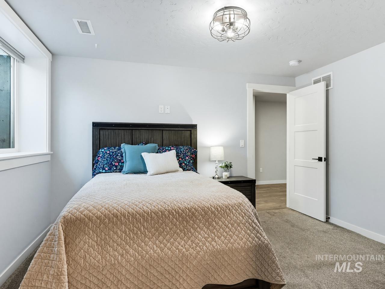 4950 West Columbia Road Nampa, ID 83687 - Photo 37 of 50 Bedroom featuring light gray walls, plush gray carpeting, a window with a white frame, and a modern ceiling light fixture