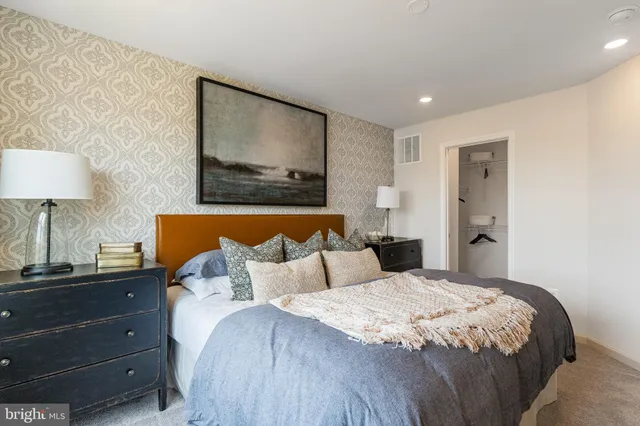 a bedroom with a bed and a lamp on dresser