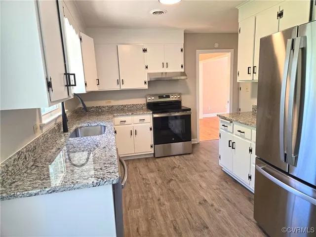 a kitchen with stainless steel appliances granite countertop a refrigerator stove and sink