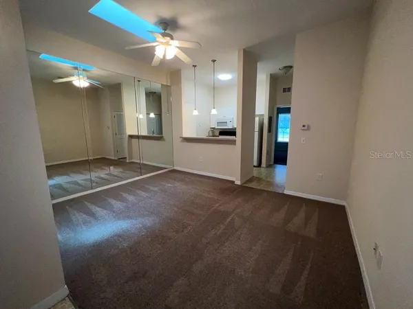 a view of an empty room with kitchen and a window