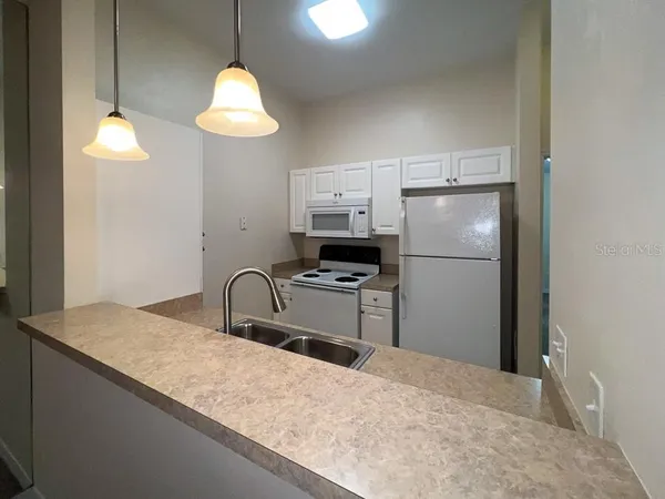 a kitchen with stainless steel appliances granite countertop a refrigerator a sink dishwasher a stove with white cabinets and wooden floor