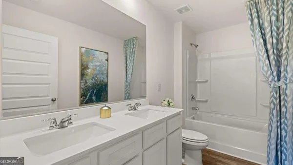 a bathroom with a bathtub shower sink vanity mirror and toilet