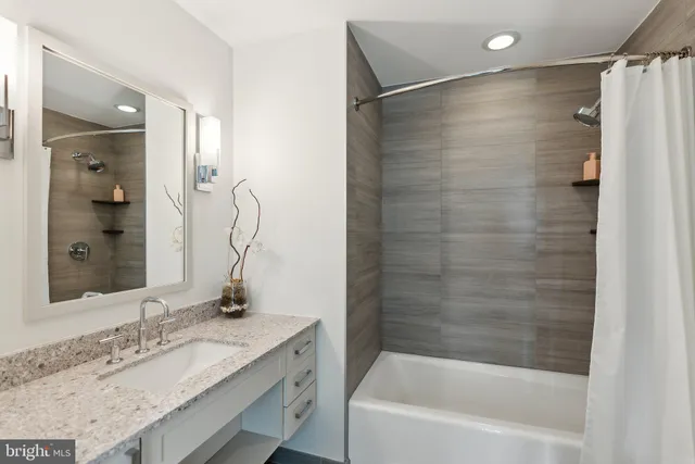 a bathroom with a granite countertop sink mirror and a bath tub