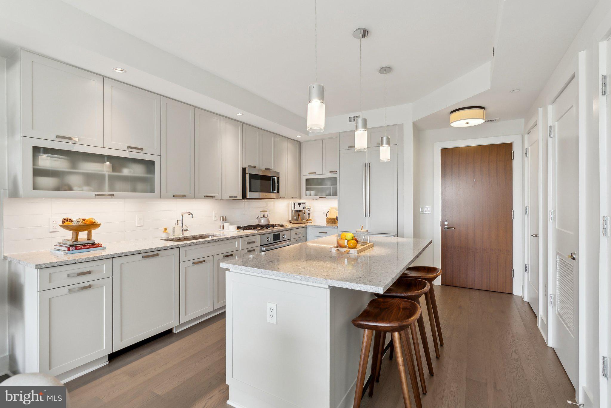 4960 Fairmont Avenue, Unit 706 Bethesda, MD 20814 - Photo 6 of 26 a kitchen with stainless steel appliances a sink a stove a refrigerator cabinets and a dining table