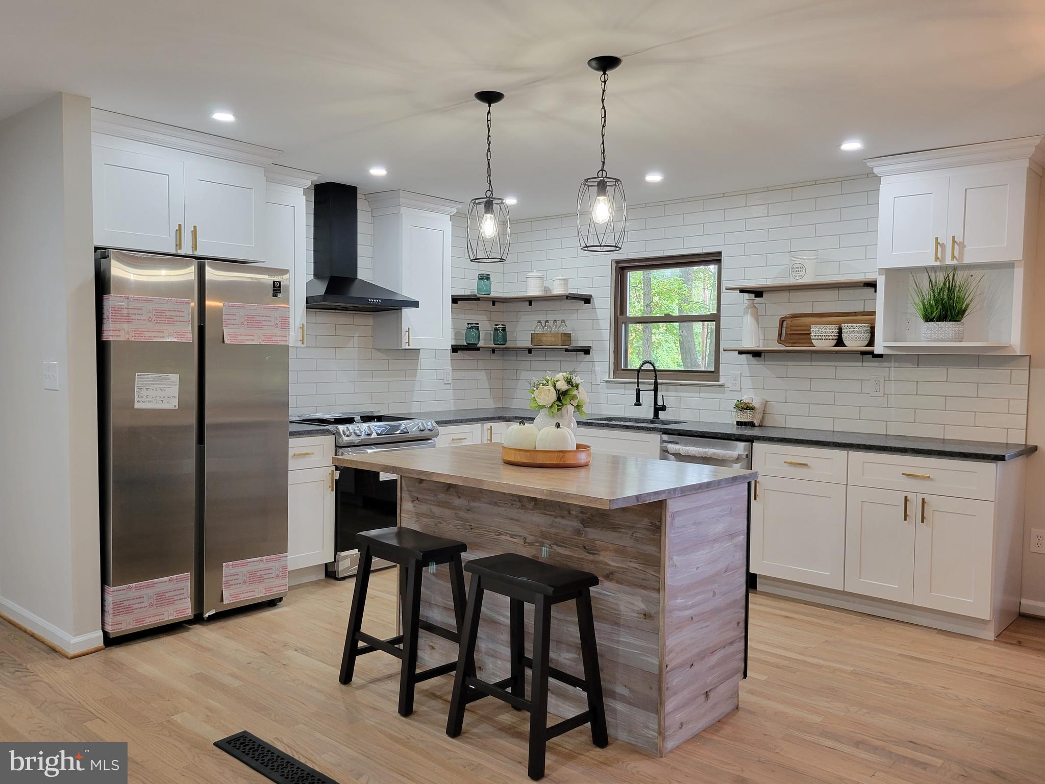a kitchen with stainless steel appliances granite countertop a kitchen island hardwood floor sink and stove