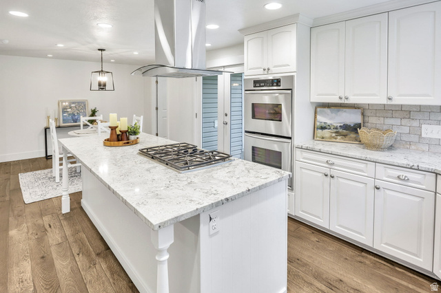 1320 Canyon Park Road Bountiful, UT 84010 - Photo 8 of 28 Kitchen with white cabinetry, island exhaust hood, light stone counters, light wood finished floors, and a breakfast bar