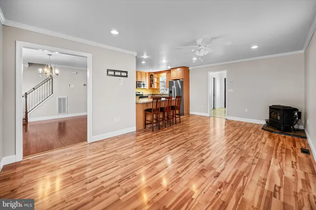 a open kitchen with granite countertop a stove top oven a sink dishwasher a dining table and chairs with wooden floor