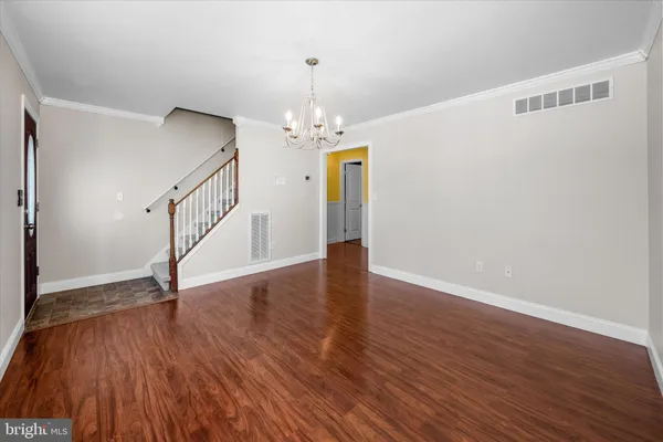 a view of an empty room with wooden floor and stairs