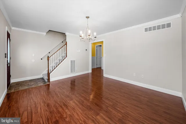 a view of an empty room with wooden floor and stairs