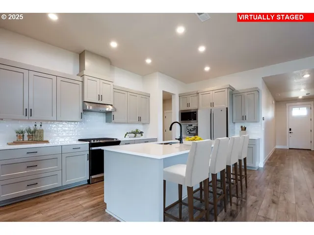 a kitchen with stainless steel appliances granite countertop a sink a stove a refrigerator a dining table and chairs