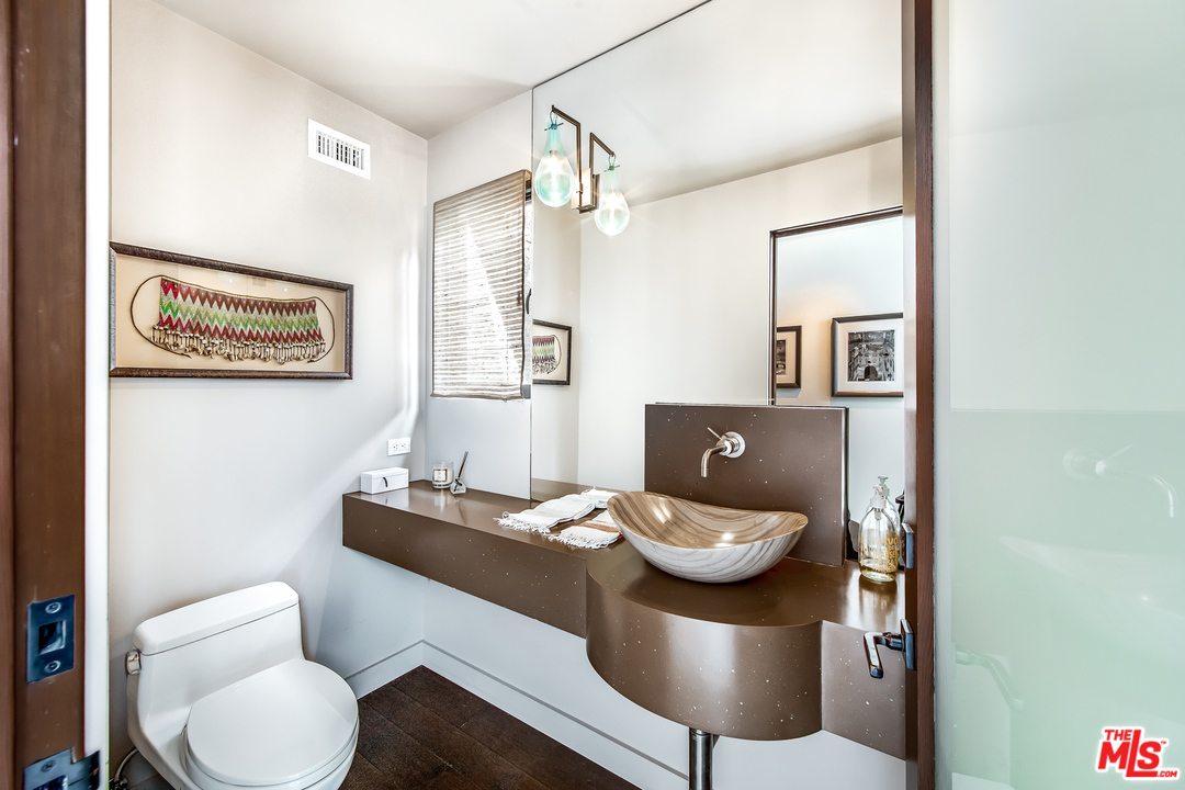 1787 Old Ranch Road Los Angeles, CA 90049 - Photo 35 of 54 a bathroom with a granite countertop toilet and a mirror