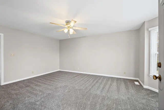 an empty room with a window and a fan