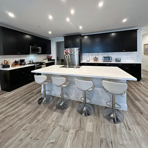 a large kitchen with stainless steel appliances a sink a stove and cabinets