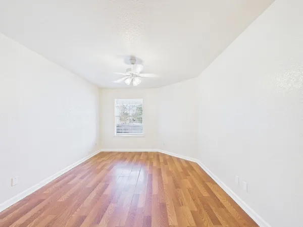 an empty room with a window and a fan