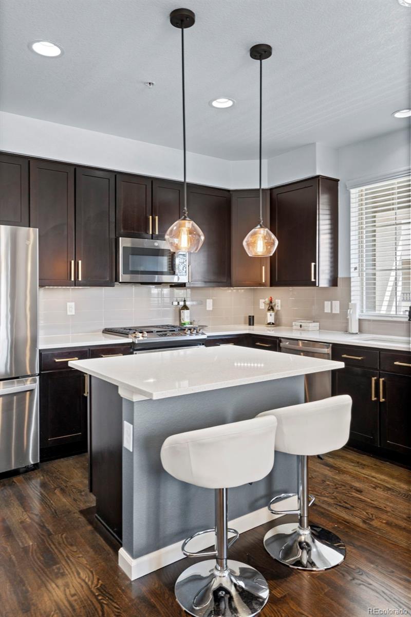 1124 Rockhurst Drive, Unit A Highlands Ranch, CO 80129 - Photo 12 of 45 a kitchen with kitchen island stainless steel appliances a sink cabinets and wooden floor