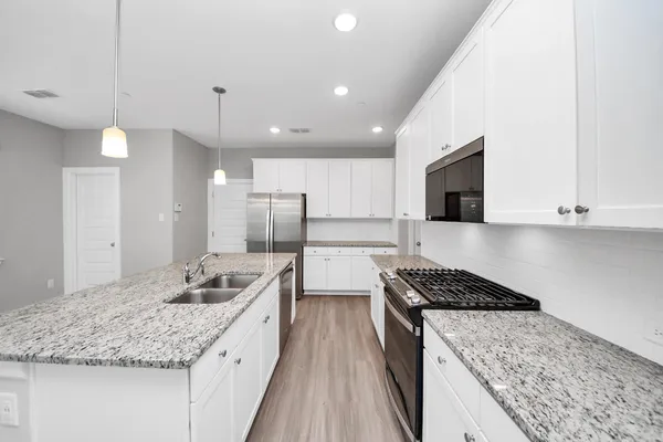 a kitchen with granite countertop a sink a counter space appliances and a window
