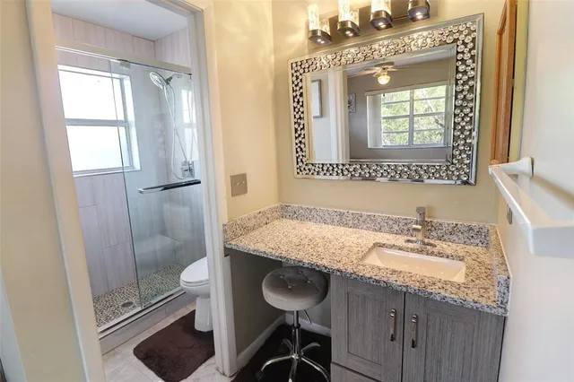 a bathroom with a granite countertop sink a mirror and a shower