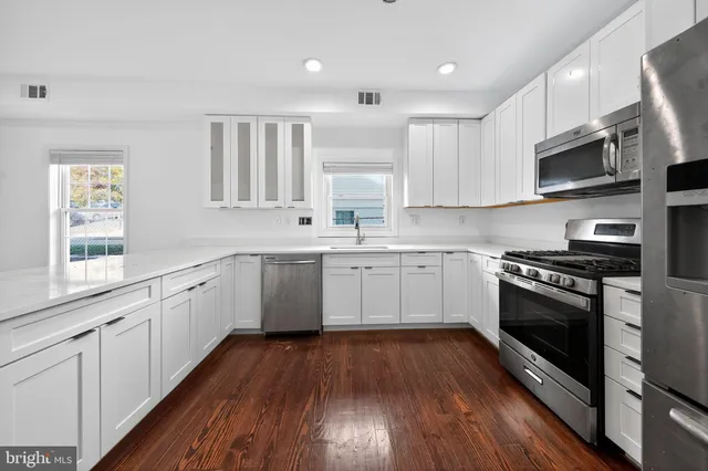 a kitchen with stainless steel appliances a white stove top oven sink and cabinets