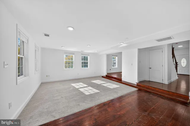 a view of an empty room with window and wooden floor