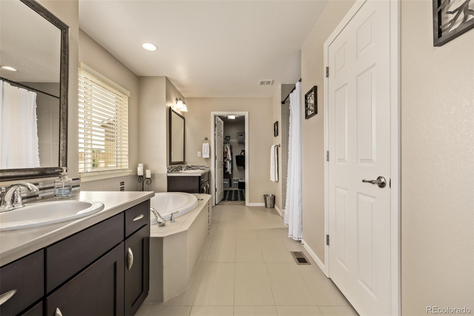 2289 Moss Place Erie, CO 80516 - Photo 22 of 45 a spacious bathroom with a double vanity sink a mirror and a shower