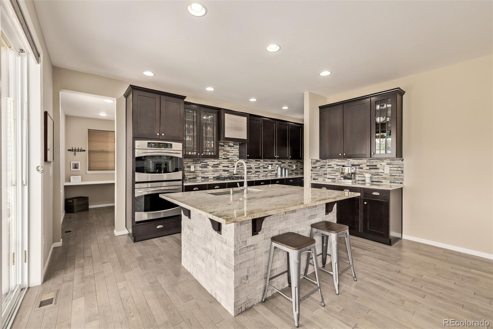2289 Moss Place Erie, CO 80516 - Photo 9 of 45 a kitchen with stainless steel appliances kitchen island granite countertop a stove top oven a sink and a refrigerator