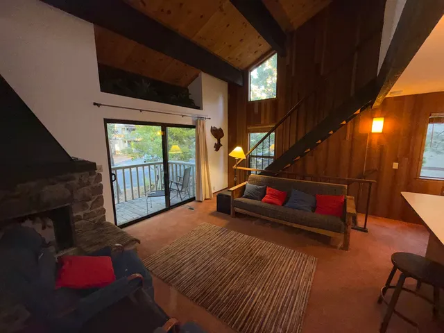 a living room with furniture a flat screen tv and a floor to ceiling window