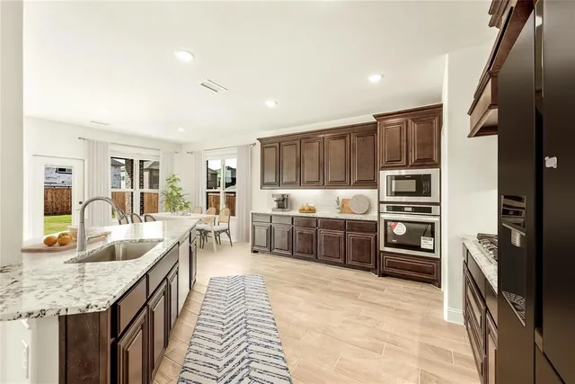 a large kitchen with kitchen island a large counter top stainless steel appliances and cabinets