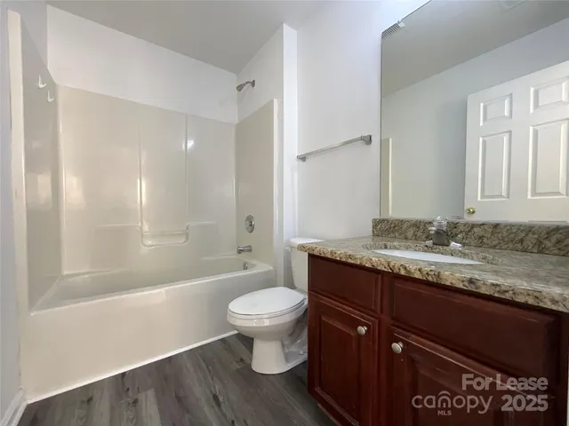 a bathroom with a granite countertop sink toilet a mirror and bathtub