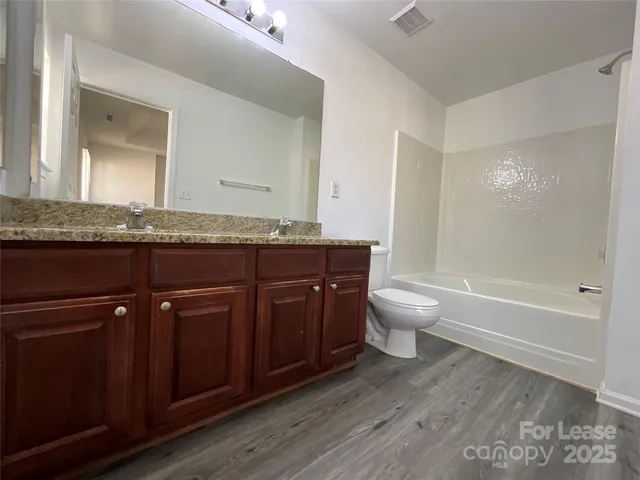 a bathroom with a granite countertop toilet a sink a mirror and a bathtub