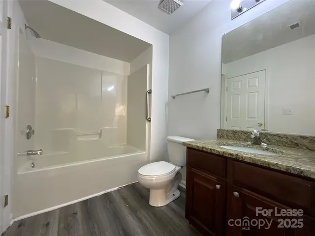 a bathroom with a granite countertop sink a toilet and shower