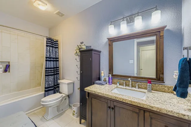 a bathroom with a granite countertop toilet a sink and a mirror