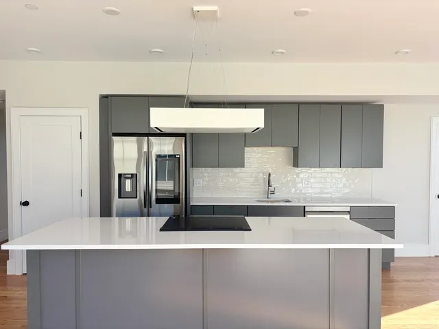 a kitchen with kitchen island a sink a stove and white cabinets