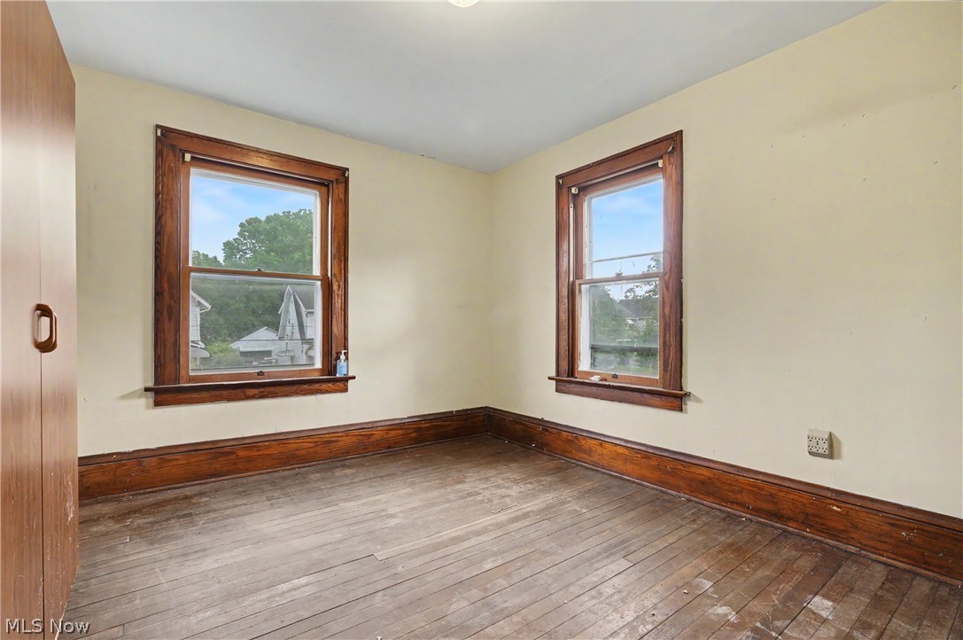 456 Delmar Avenue Akron, OH 44310 - Photo 22 of 27 Interior room with two windows featuring wood trim, wood-finish flooring, and light-toned walls