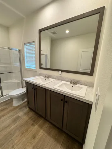 a bathroom with a double vanity sink and mirror with toilet