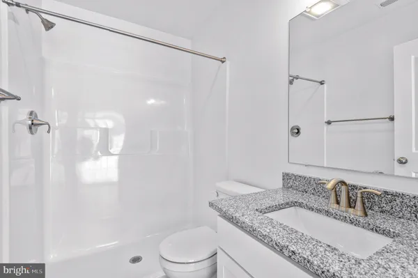a bathroom with a granite countertop sink a toilet and shower